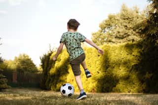 Kind speelt voetbal in tuin